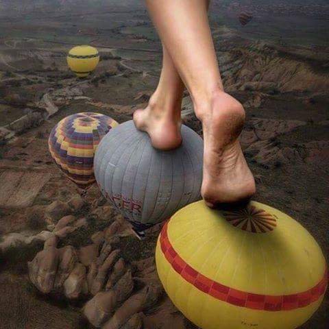 Bare feet stepping across hot-air balloons high above the ground