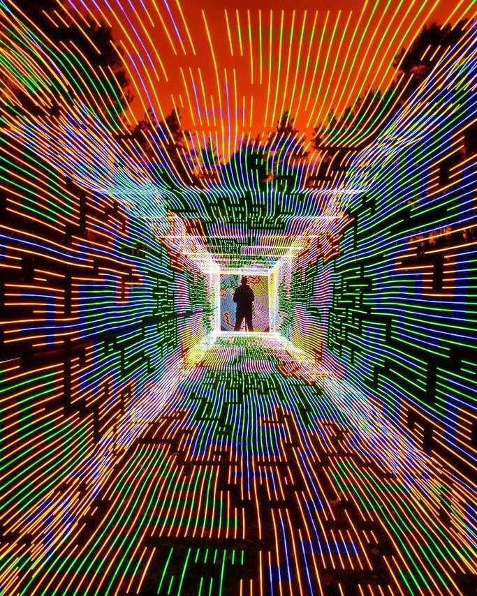 A figure at the end of a glowing corridor drawn in coloured light