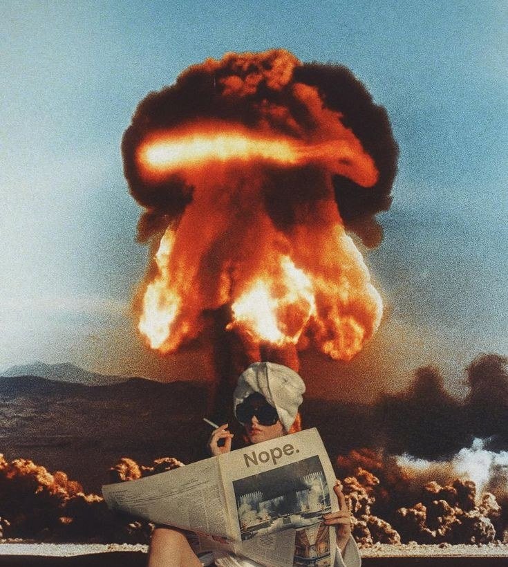 A woman calmly reading a newspaper headlined Nope in front of a mushroom cloud
